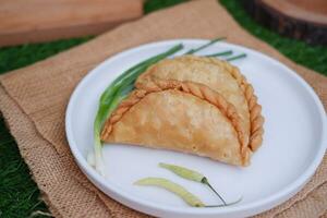 Curry puff or Pastel Goreng is Pastry Popular in Indonesia. fried pastry with filling of sauted vegetable, chicken and boiled egg. accompanied with  sauce or raw chilli pepper photo