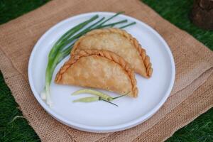 Curry puff or Pastel Goreng is Pastry Popular in Indonesia. fried pastry with filling of sauted vegetable, chicken and boiled egg. accompanied with  sauce or raw chilli pepper photo