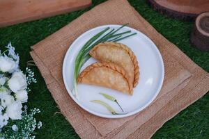 Curry puff or Pastel Goreng is Pastry Popular in Indonesia. fried pastry with filling of sauted vegetable, chicken and boiled egg. accompanied with  sauce or raw chilli pepper photo