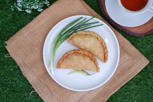 Curry puff or Pastel Goreng is Pastry Popular in Indonesia. fried pastry with filling of sauted vegetable, chicken and boiled egg. accompanied with  sauce or raw chilli pepper photo