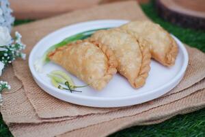 Curry puff or Pastel Goreng is Pastry Popular in Indonesia. fried pastry with filling of sauted vegetable, chicken and boiled egg. accompanied with  sauce or raw chilli pepper photo