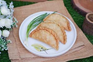 Curry puff or Pastel Goreng is Pastry Popular in Indonesia. fried pastry with filling of sauted vegetable, chicken and boiled egg. accompanied with  sauce or raw chilli pepper photo