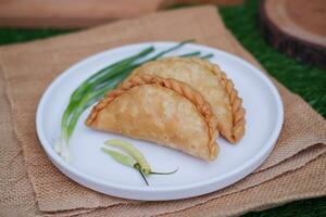Curry puff or Pastel Goreng is Pastry Popular in Indonesia. fried pastry with filling of sauted vegetable, chicken and boiled egg. accompanied with  sauce or raw chilli pepper photo