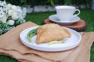 Curry puff or Pastel Goreng is Pastry Popular in Indonesia. fried pastry with filling of sauted vegetable, chicken and boiled egg. accompanied with  sauce or raw chilli pepper photo