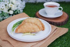 Curry puff or Pastel Goreng is Pastry Popular in Indonesia. fried pastry with filling of sauted vegetable, chicken and boiled egg. accompanied with  sauce or raw chilli pepper photo