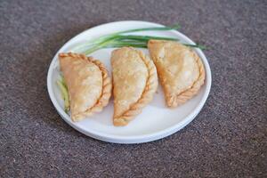 Curry puff or Pastel Goreng is Pastry Popular in Indonesia. fried pastry with filling of sauted vegetable, chicken and boiled egg. accompanied with  sauce or raw chilli pepper photo