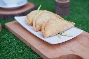 Curry puff or Pastel Goreng is Pastry Popular in Indonesia. fried pastry with filling of sauted vegetable, chicken and boiled egg. accompanied with  sauce or raw chilli pepper photo