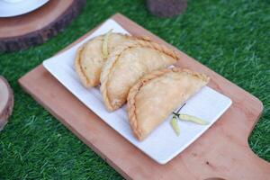 Curry puff or Pastel Goreng is Pastry Popular in Indonesia. fried pastry with filling of sauted vegetable, chicken and boiled egg. accompanied with  sauce or raw chilli pepper photo