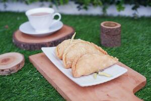 Curry puff or Pastel Goreng is Pastry Popular in Indonesia. fried pastry with filling of sauted vegetable, chicken and boiled egg. accompanied with  sauce or raw chilli pepper photo
