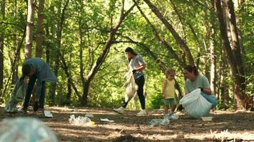 een groep van vrijwilligers met een kind schoon omhoog vuilnis in de bos.aarde dag, opslaan planeet, opslaan de wereld, liefde natuur. video