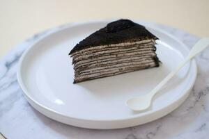 Piece of homemade chocolate crepes cake on a white plate photo