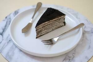 Piece of homemade chocolate crepes cake on a white plate photo