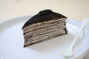 Piece of homemade chocolate crepes cake on a white plate photo
