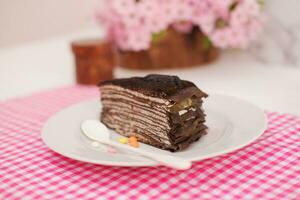 Piece of homemade chocolate crepes cake on a white plate photo