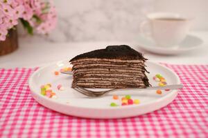 Piece of homemade chocolate crepes cake on a white plate photo