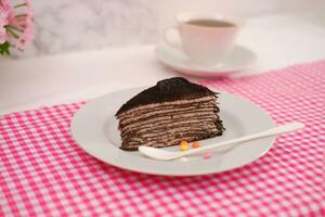 Piece of homemade chocolate crepes cake on a white plate photo