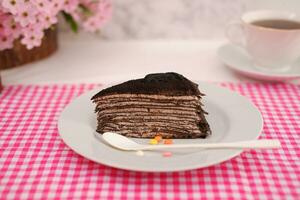 Piece of homemade chocolate crepes cake on a white plate photo