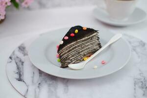 Piece of homemade chocolate crepes cake on a white plate photo