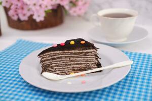 Piece of homemade chocolate crepes cake on a white plate photo