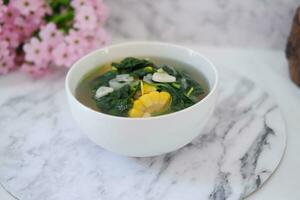 Sayur Bening Daun kelor jagung or Moringa Oleifera clear soup with sweet corn served in bowl photo