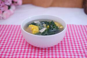 Sayur Bening Daun kelor jagung or Moringa Oleifera clear soup with sweet corn served in bowl photo