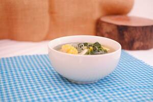 Sayur Bening Daun kelor jagung or Moringa Oleifera clear soup with sweet corn served in bowl photo