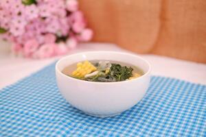 Sayur Bening Daun kelor jagung or Moringa Oleifera clear soup with sweet corn served in bowl photo