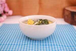 Sayur Bening Daun kelor jagung or Moringa Oleifera clear soup with sweet corn served in bowl photo