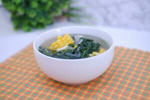 Sayur Bening Daun kelor jagung or Moringa Oleifera clear soup with sweet corn served in bowl photo