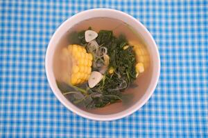 Sayur Bening Daun kelor jagung or Moringa Oleifera clear soup with sweet corn served in bowl photo