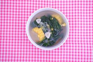 Sayur Bening Daun kelor jagung or Moringa Oleifera clear soup with sweet corn served in bowl photo