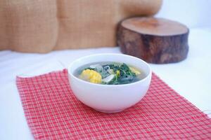 Sayur Bening Daun kelor jagung or Moringa Oleifera clear soup with sweet corn served in bowl photo