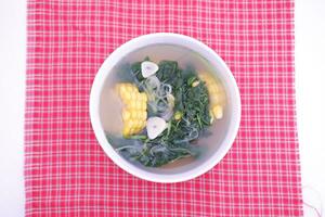 Sayur Bening Daun kelor jagung or Moringa Oleifera clear soup with sweet corn served in bowl photo
