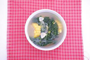 Sayur Bening Daun kelor jagung or Moringa Oleifera clear soup with sweet corn served in bowl photo