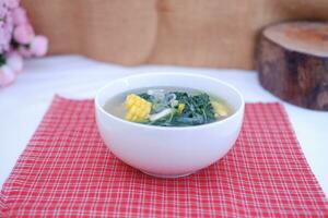 Sayur Bening Daun kelor jagung or Moringa Oleifera clear soup with sweet corn served in bowl photo