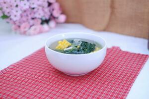 Sayur Bening Daun kelor jagung or Moringa Oleifera clear soup with sweet corn served in bowl photo