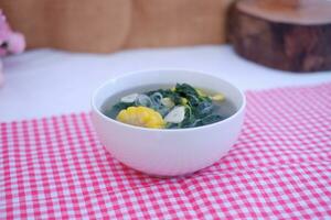 Sayur Bening Daun kelor jagung or Moringa Oleifera clear soup with sweet corn served in bowl photo