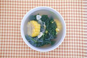 Sayur Bening Daun kelor jagung or Moringa Oleifera clear soup with sweet corn served in bowl photo
