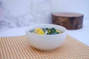 Sayur Bening Daun kelor jagung or Moringa Oleifera clear soup with sweet corn served in bowl photo