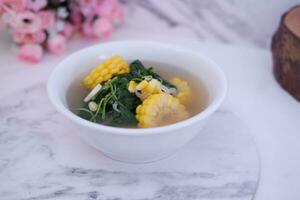 Sayur Bening Daun kelor jagung or Moringa Oleifera clear soup with sweet corn served in bowl photo