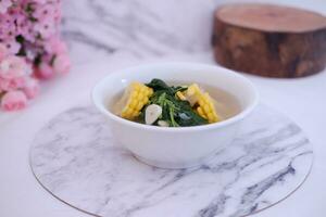 Sayur Bening Daun kelor jagung or Moringa Oleifera clear soup with sweet corn served in bowl photo