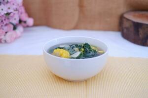 Sayur Bening Daun kelor jagung or Moringa Oleifera clear soup with sweet corn served in bowl photo