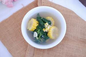 Sayur Bening Daun kelor jagung or Moringa Oleifera clear soup with sweet corn served in bowl photo