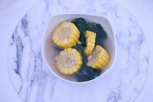 Sayur Bening Daun kelor jagung or Moringa Oleifera clear soup with sweet corn served in bowl photo