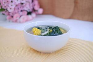 Sayur Bening Daun kelor jagung or Moringa Oleifera clear soup with sweet corn served in bowl photo