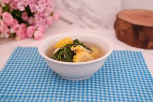 Sayur Bening Daun kelor jagung or Moringa Oleifera clear soup with sweet corn served in bowl photo