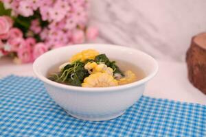 Sayur Bening Daun kelor jagung or Moringa Oleifera clear soup with sweet corn served in bowl photo