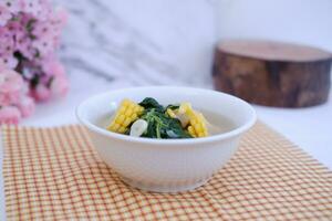Sayur Bening Daun kelor jagung or Moringa Oleifera clear soup with sweet corn served in bowl photo