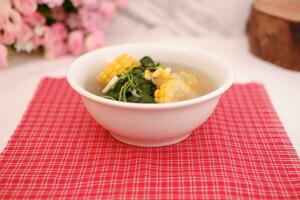 Sayur Bening Daun kelor jagung or Moringa Oleifera clear soup with sweet corn served in bowl photo