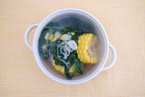 Sayur Bening Daun kelor jagung or Moringa Oleifera clear soup with sweet corn served in bowl photo